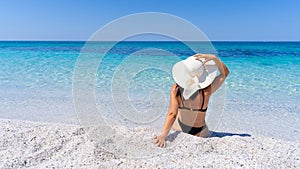 girl with white straw hat relaxes in front of the sea photo